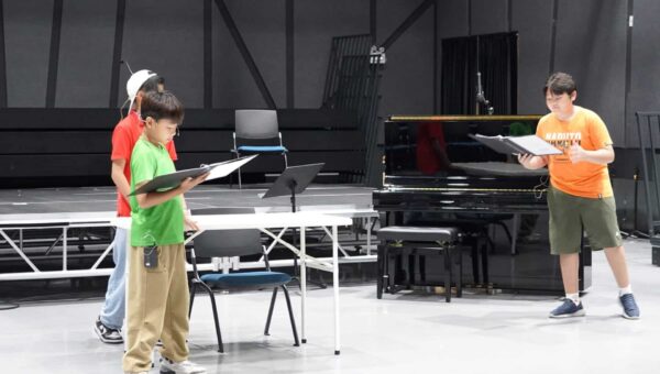 BASIS International School Bangkok students rehearsing from scores beside a piano