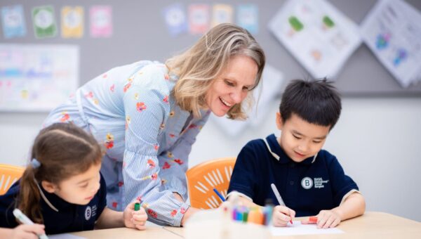 A teacher helping BASIS International School Bangkok students with an art and drawing activity