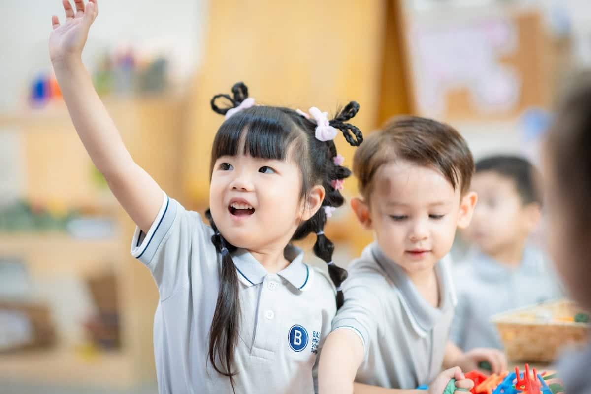 An enthusiastic student raising her hand during class at an international primary school