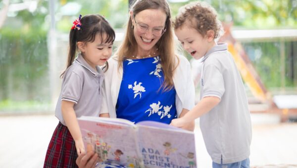 A teacher reading a picture book aloud to young BASIS International School Bangkok students