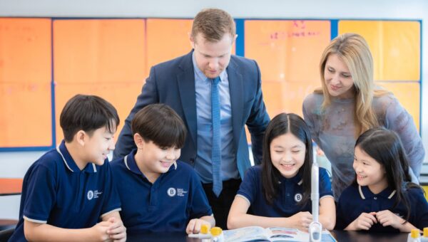A teacher leading a lesson with BASIS International School Bangkok students at a screen