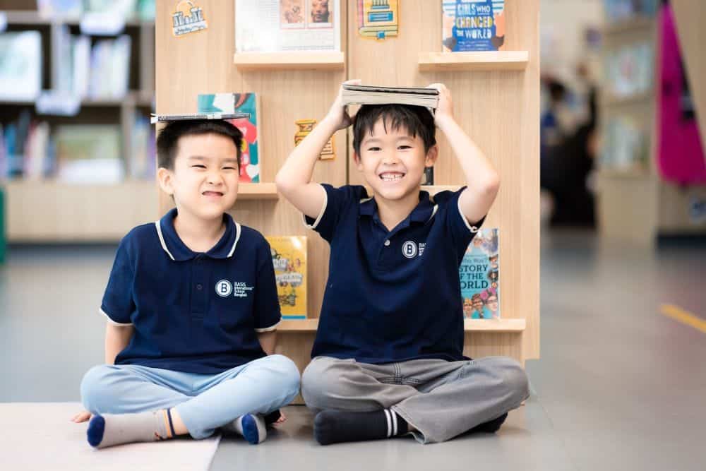 two young students at BASIS International School have fun in the library.