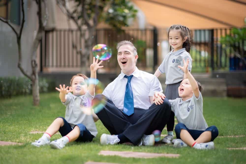 Children with their teacher playing with bubbles at BASIS International School in Bangkok