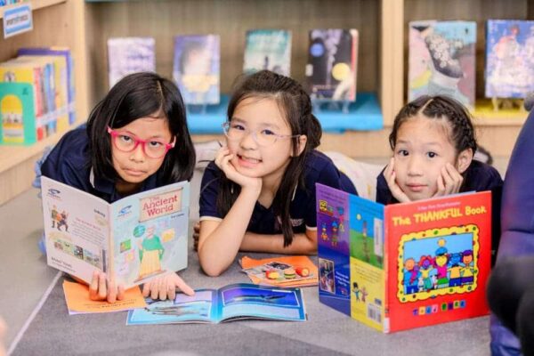 Smiling BASIS International School Bangkok students holding up books