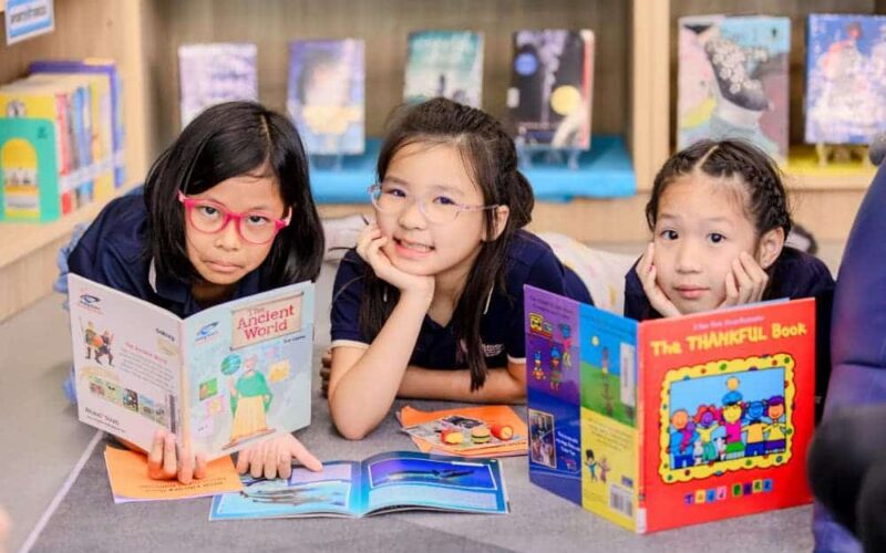 Smiling BASIS International School Bangkok students holding up books