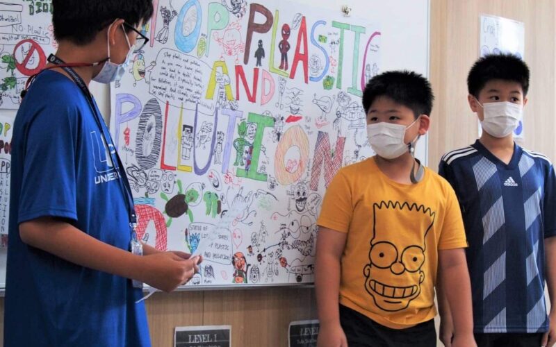 BASIS International School Bangkok students in front of a display of their artwork